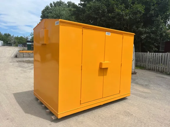 An orange Laurin steel storage cabinet standing outdoors on a gravel yard